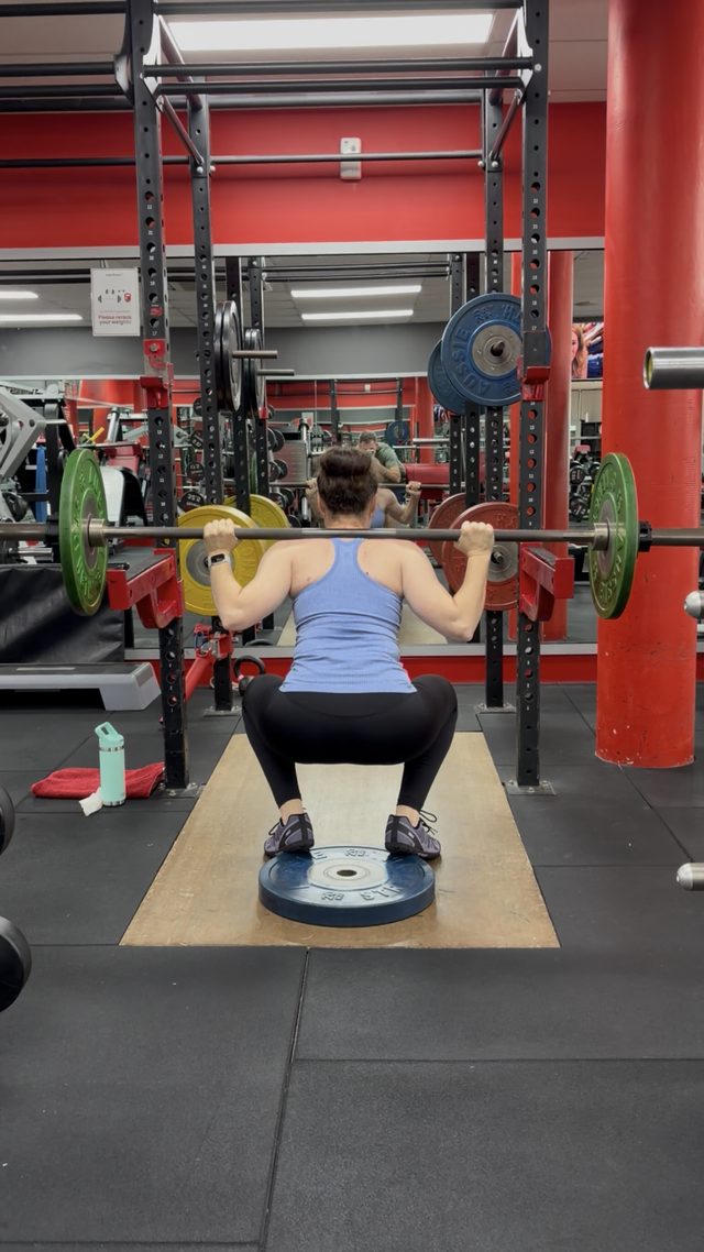 Claire in the bottom of a barbell back squat at the gym